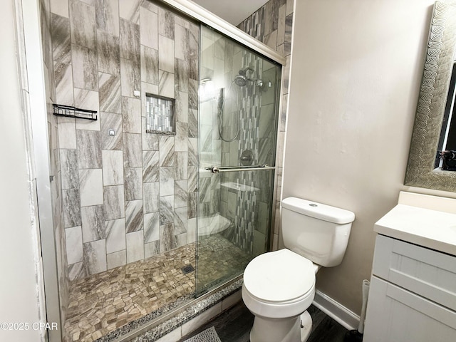 full bath with toilet, a stall shower, baseboards, and vanity