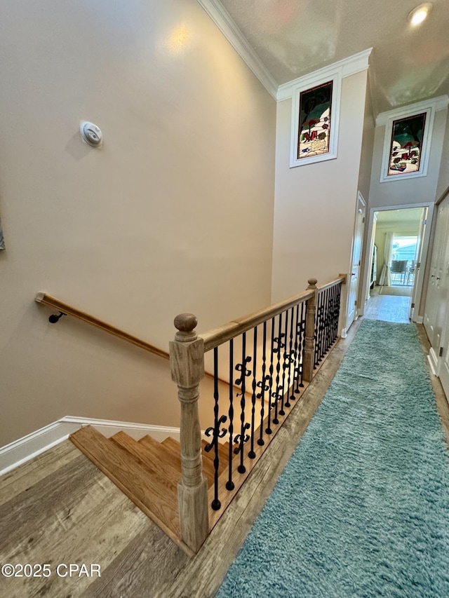 stairway with hardwood / wood-style flooring and ornamental molding