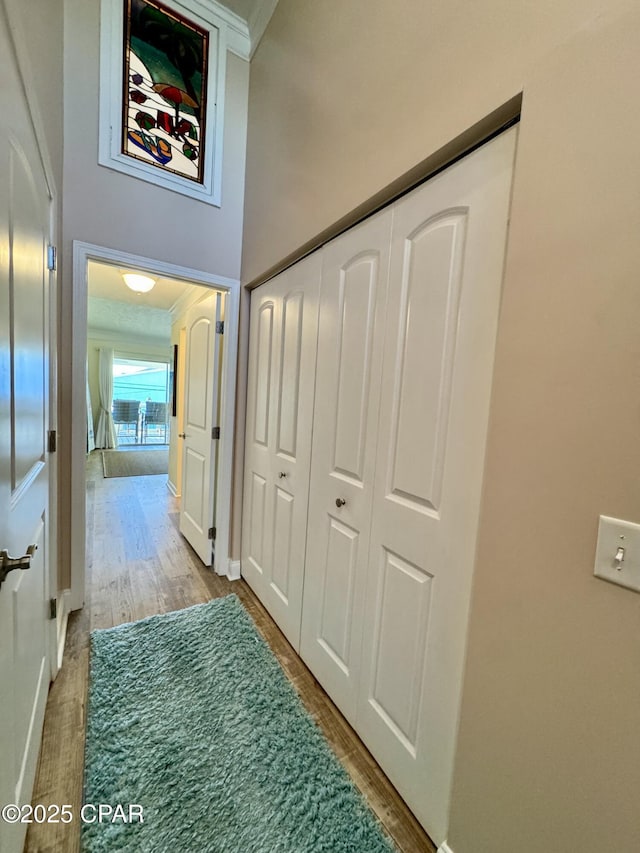 hallway featuring a high ceiling, crown molding, and hardwood / wood-style floors