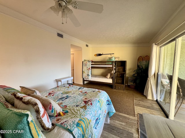 bedroom with hardwood / wood-style floors, a textured ceiling, ornamental molding, and ceiling fan