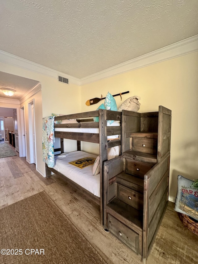 bedroom featuring crown molding, hardwood / wood-style floors, and a textured ceiling