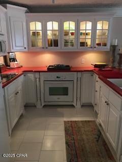 kitchen with light tile patterned floors, white appliances, and white cabinets