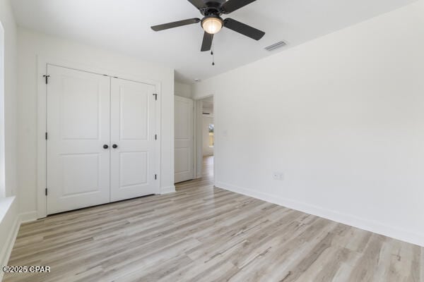 unfurnished bedroom with ceiling fan, light hardwood / wood-style floors, and a closet