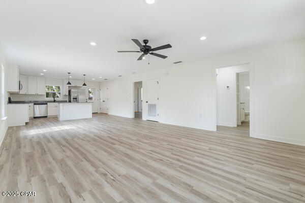 unfurnished living room with sink, ceiling fan, and light hardwood / wood-style flooring