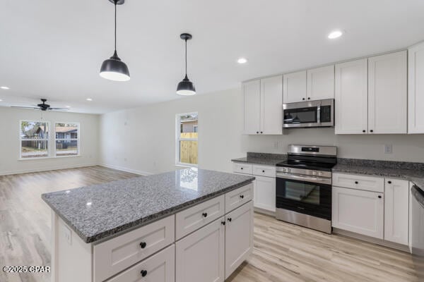 kitchen featuring white cabinetry, pendant lighting, dark stone counters, and appliances with stainless steel finishes