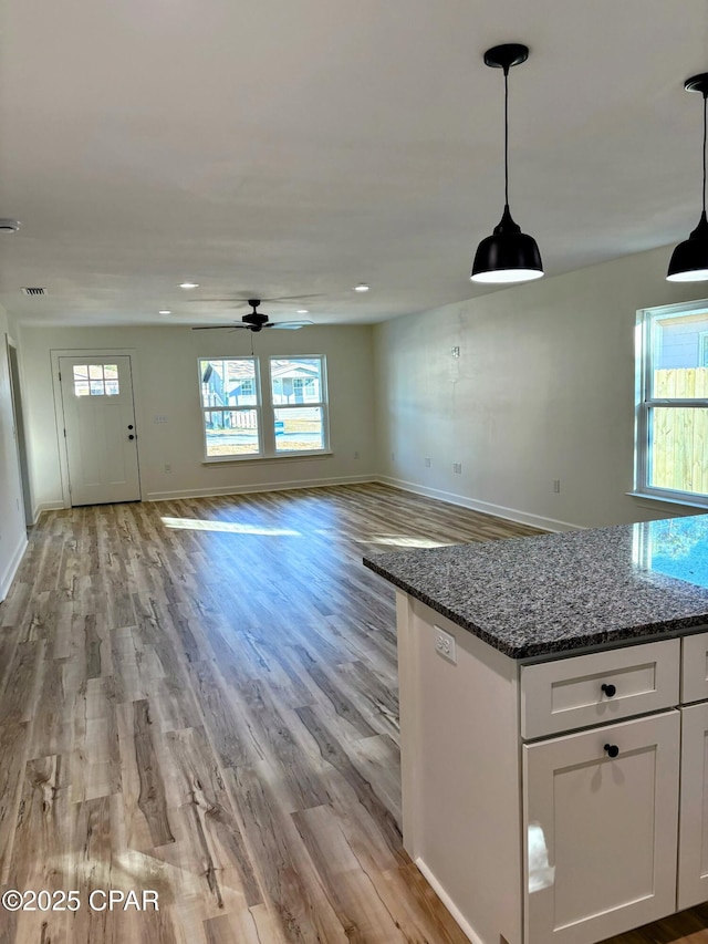 kitchen featuring dark stone countertops, decorative light fixtures, light hardwood / wood-style floors, and white cabinets