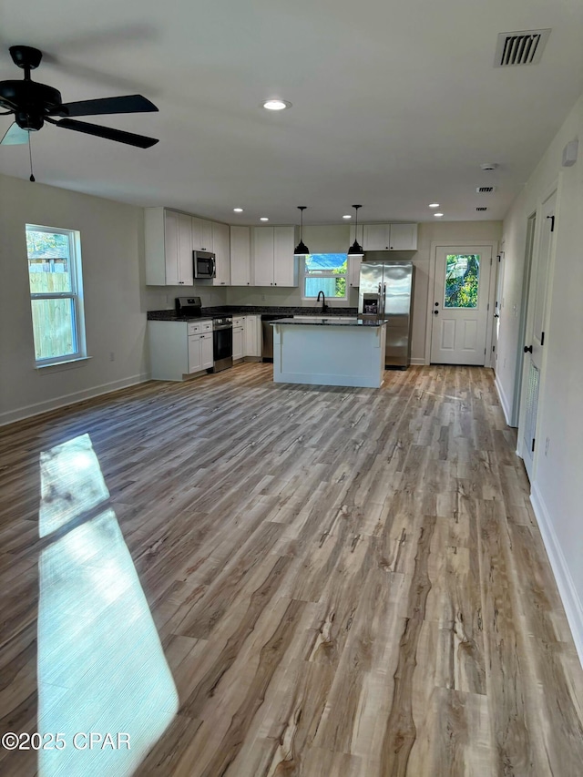 kitchen featuring decorative light fixtures, a kitchen island, stainless steel appliances, light hardwood / wood-style floors, and white cabinets