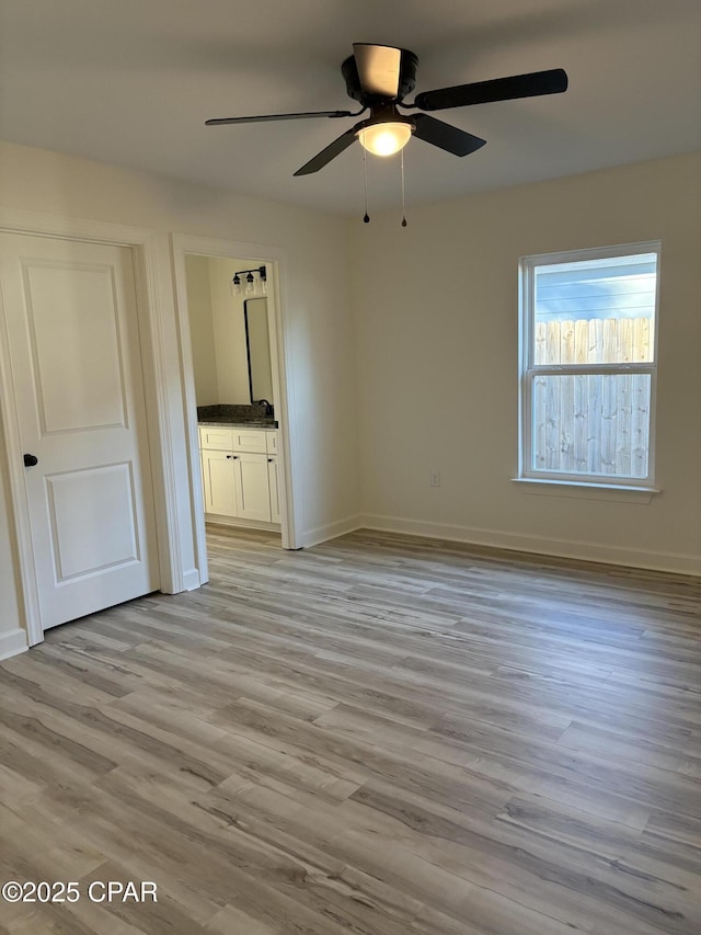 unfurnished bedroom with connected bathroom, ceiling fan, and light wood-type flooring