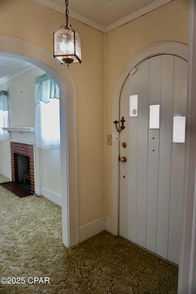 carpeted entryway with crown molding and a fireplace