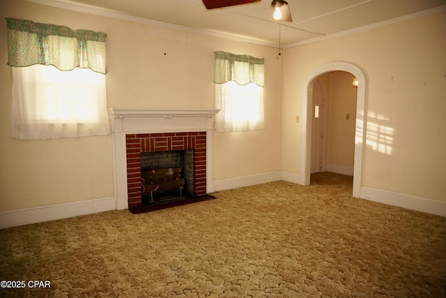 unfurnished living room with ceiling fan, ornamental molding, carpet flooring, and a brick fireplace