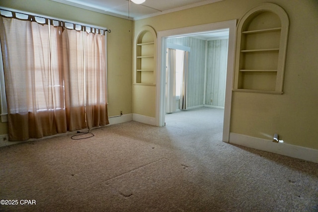 unfurnished room with built in shelves and carpet flooring