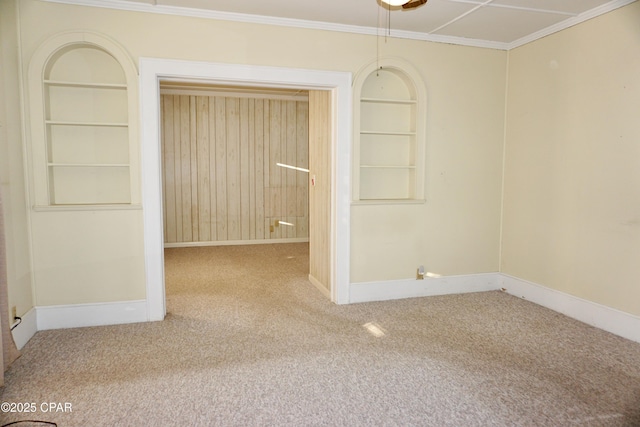 empty room with ornamental molding, built in features, and carpet