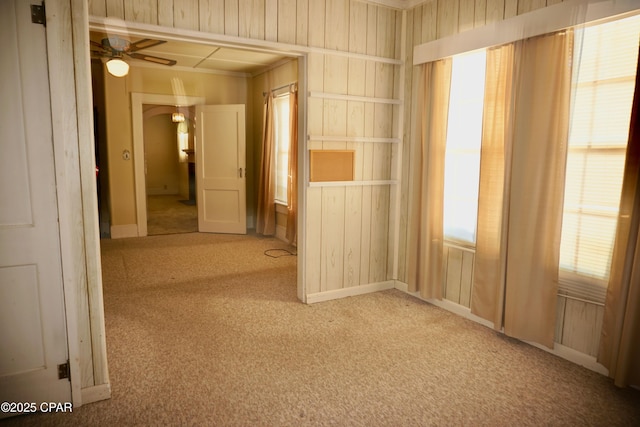 carpeted empty room with ceiling fan and wooden walls