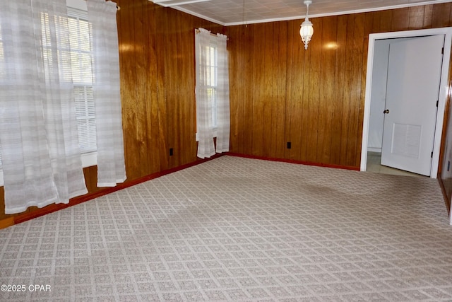 carpeted spare room with ornamental molding and wooden walls