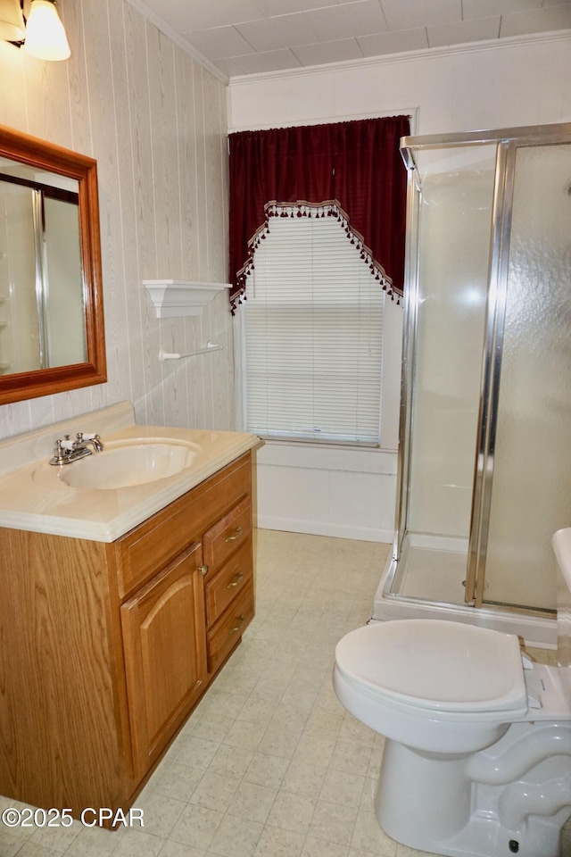 bathroom featuring toilet, an enclosed shower, crown molding, vanity, and wooden walls