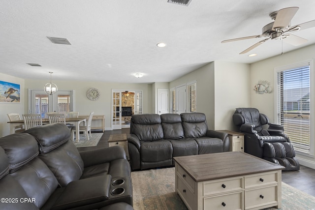 living room featuring ceiling fan, dark wood-type flooring, and a textured ceiling