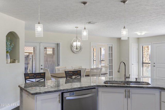 kitchen with dark stone counters, pendant lighting, stainless steel dishwasher, white cabinets, and sink