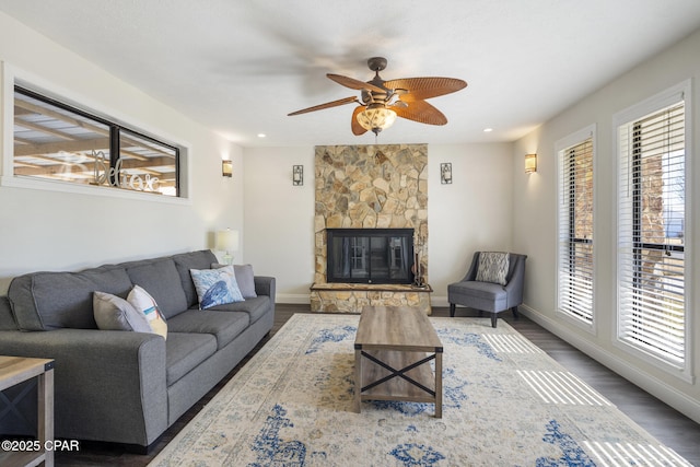 living room featuring ceiling fan, a fireplace, and dark wood-type flooring