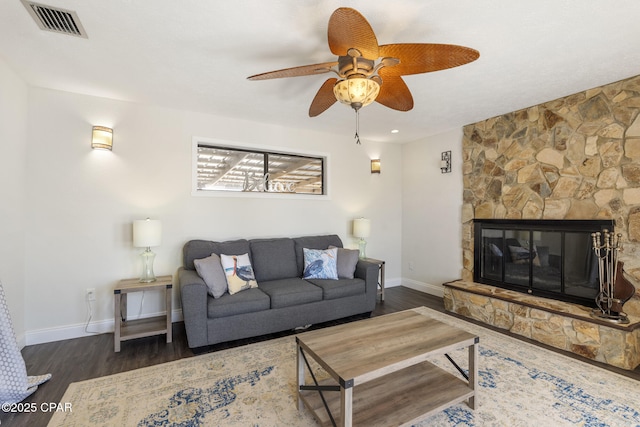 living room featuring dark wood-type flooring, ceiling fan, and a fireplace