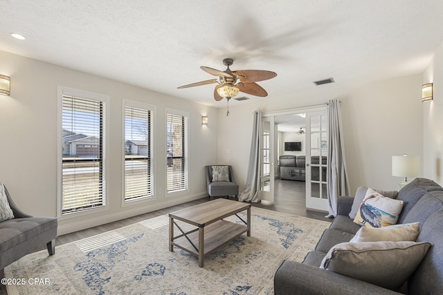 living room featuring hardwood / wood-style flooring, a textured ceiling, and ceiling fan