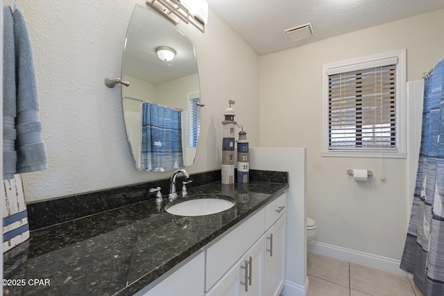 bathroom with toilet, vanity, tile patterned flooring, and a textured ceiling