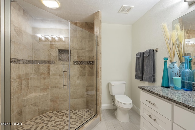 bathroom featuring toilet, a textured ceiling, walk in shower, and vanity