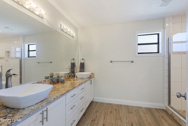 bathroom with a shower with shower door, hardwood / wood-style floors, and vanity