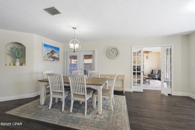 dining room featuring dark wood-type flooring, a textured ceiling, a notable chandelier, and french doors