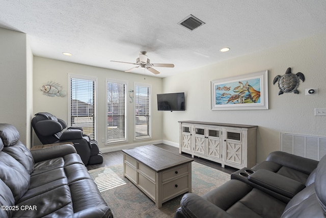 living room featuring ceiling fan, a textured ceiling, and hardwood / wood-style floors