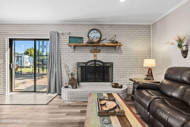 living room featuring brick wall, a fireplace, wood-type flooring, and ornamental molding