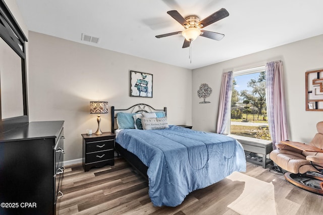 bedroom featuring ceiling fan, multiple windows, and hardwood / wood-style floors