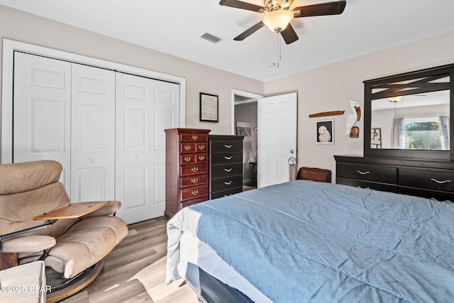 bedroom with light wood-type flooring, ceiling fan, and a closet