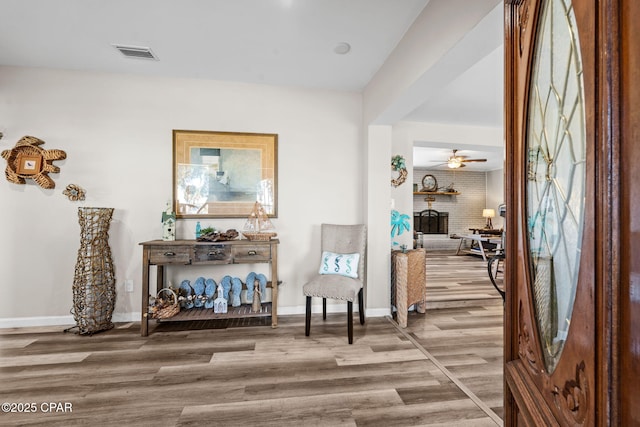 living area with ceiling fan, a fireplace, and hardwood / wood-style flooring