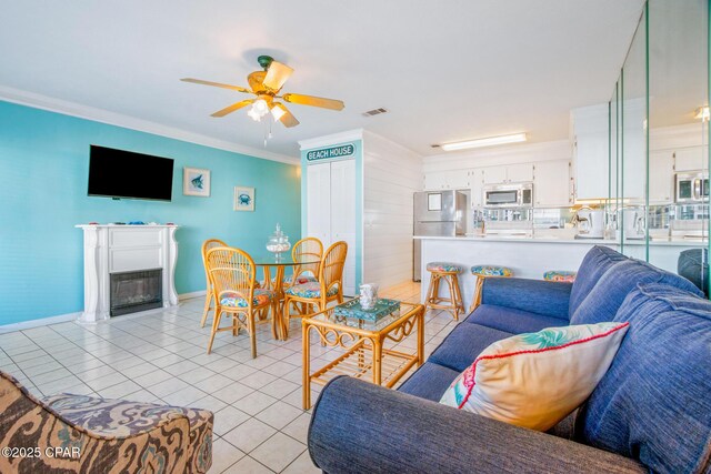 living room featuring ceiling fan, light tile patterned floors, and crown molding