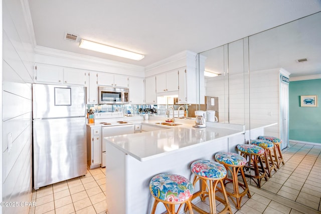 kitchen with pendant lighting, white cabinetry, stainless steel appliances, kitchen peninsula, and light tile patterned floors