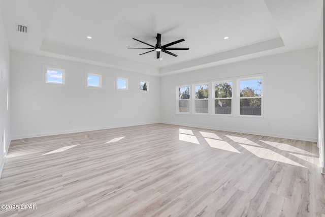 spare room featuring ceiling fan, light hardwood / wood-style floors, and a tray ceiling