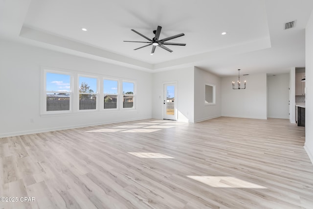 unfurnished living room with light wood-type flooring and a raised ceiling