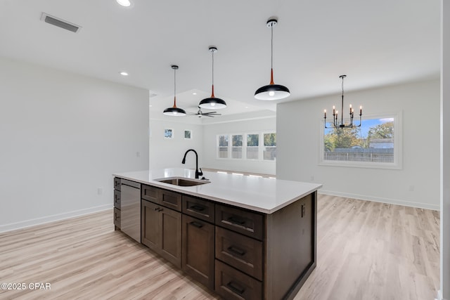 kitchen featuring light hardwood / wood-style flooring, dishwasher, sink, decorative light fixtures, and an island with sink