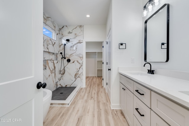 bathroom featuring wood-type flooring, vanity, and a tile shower