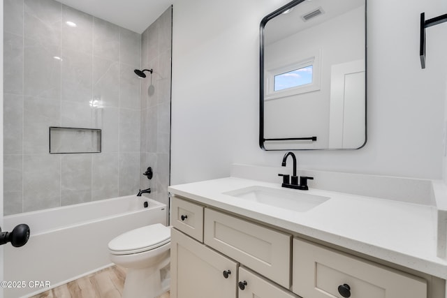 full bathroom with tiled shower / bath combo, hardwood / wood-style flooring, toilet, and vanity