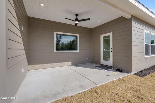 view of exterior entry featuring ceiling fan and a patio