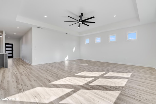 unfurnished room featuring light hardwood / wood-style floors, a raised ceiling, and ceiling fan