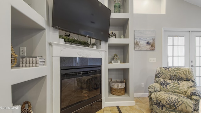 tiled living room with a tile fireplace and built in shelves