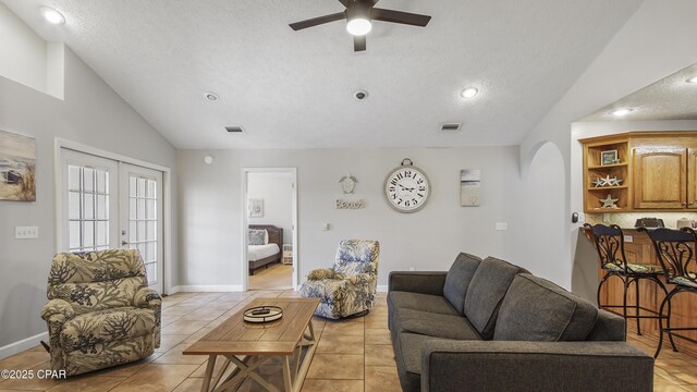 tiled living room featuring a textured ceiling, ceiling fan, lofted ceiling, and built in shelves