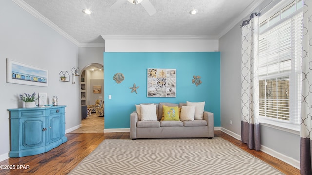 living room with ceiling fan, light hardwood / wood-style flooring, a textured ceiling, and ornamental molding