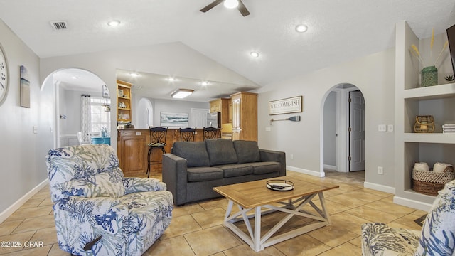 living room featuring a textured ceiling, built in shelves, vaulted ceiling, ceiling fan, and light tile patterned floors