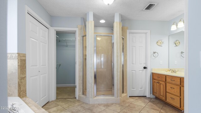 bathroom with a textured ceiling, tile patterned flooring, a shower with door, and vanity