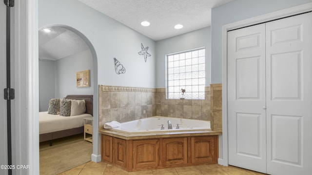 bathroom featuring a washtub, a textured ceiling, and tile patterned floors