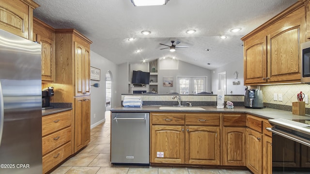 kitchen with ceiling fan, appliances with stainless steel finishes, a textured ceiling, vaulted ceiling, and sink