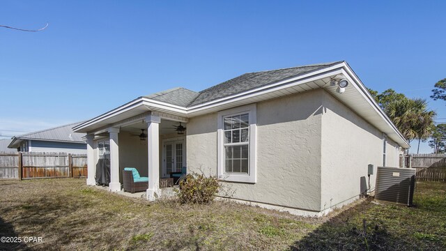 back of property featuring central AC unit, ceiling fan, and a lawn